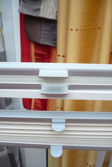 Weißer Fensterrahmen mit gelb-rot gemusterten Vorhängen im Hintergrund.